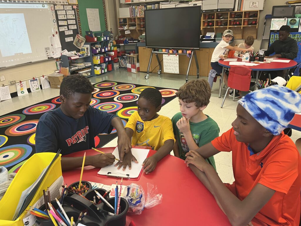 middle school student tracing hands of elementary student